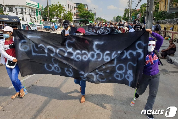 시위대들이 '우리는 민주주의를 원한다'라고 적힌 플래카드를 들고 양곤 시내를 걷고 있다. © AFP=뉴스1 © News1 원태성 기자