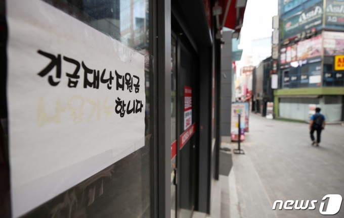 22일 오전 서울 중구 명동의 한 점포에 재난지원금 사용 가능함을 알리는 안내문 옆으로 한산한 거리가 보이고 있다. /사진=뉴스1