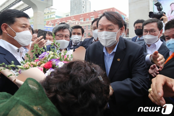  야권 대선주자인 윤석열 전 검찰총장이 20일 낮 대구 서문시장을 찾아 환영의 꽃다발을 받고 있다. 2021.7.20/뉴스1  