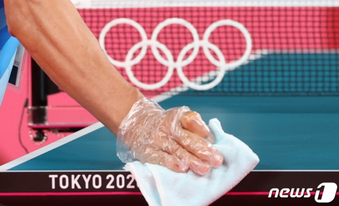 (도쿄=뉴스1) 송원영 기자 = 2020 도쿄 올림픽을 3일 앞둔 20일 일본 도쿄체육관에서 올림픽 관계자가 신종 코로나바이러스 감염증(코로나19) 확산 방지를 위해 탁구대를 소독하고 있다. 2021.7.20/뉴스1