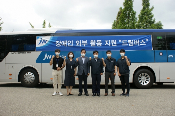 서명준 JW중외제약 제품플랜트장(왼쪽부터 네 번째)과 이창호 아산시장애인복지관 관장(왼쪽부터 세 번째)을 비롯한 관계자들이 '드림버스’ 앞에서 기념촬영하고 있다./사진=JW중외제약