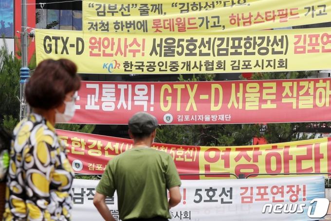 (김포=뉴스1) 민경석 기자 = 그동안 논란을 빚었던 GTX-D(서부권 광역급행철도) 노선이 정부 초안대로 김포와 부천만을 연결하는 것으로 확정됐다. 정부는 대신 GTX-B 사업자와 협의를 통해 신도림과 여의도, 용산 등 서울 도심까지 열차 환승 없이 직결 운행하는 방안을 추진한다고 밝혔다. 30일 경기도 김포시 김포골드라인 장기역 네거리에 GTX-D 노선의 서울 직결 및 5호선 연장 등을 촉구하는 내용의 현수막이 걸려 있다. 2021.6.30/뉴스1