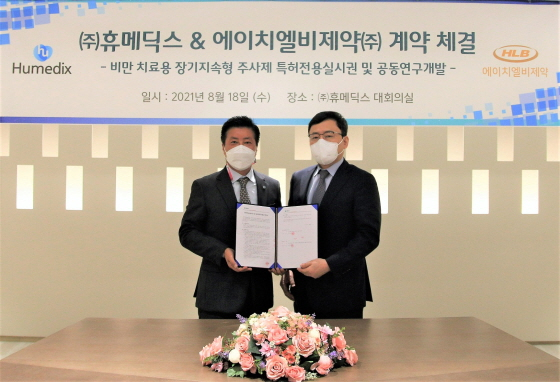 지난 8월 18일 김진환 휴메딕스 대표(왼쪽)와 전복환 에이치엘비제약 대표(오른쪽)가 '비만치료 장기지속형주사제 공동연구개발 계약'을 체결하고 기념촬영을 하고있다./사진제공=휴온스
