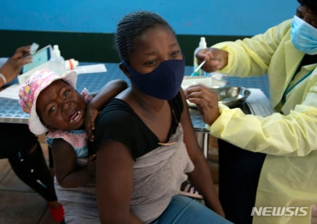 [요하네스버그=AP/뉴시스] 조 파흘라 남아공 보건부 장관은 25일(현지시간) 남아프리카공화국에서 코로나19 새 변이가 발견됐다고 밝혔다. 이 변이종은 스파이크 단백질에 유전자 변이 32개를 보유, 전파력이 더욱더 강해 백신을 무력화할 있다는 우려가 나온다. 사진은 10월 21일 요하네스버그 인근에서 아기를 업은 한 여성이 화이자 백신을 접종하는 모습. 2021.11.26.