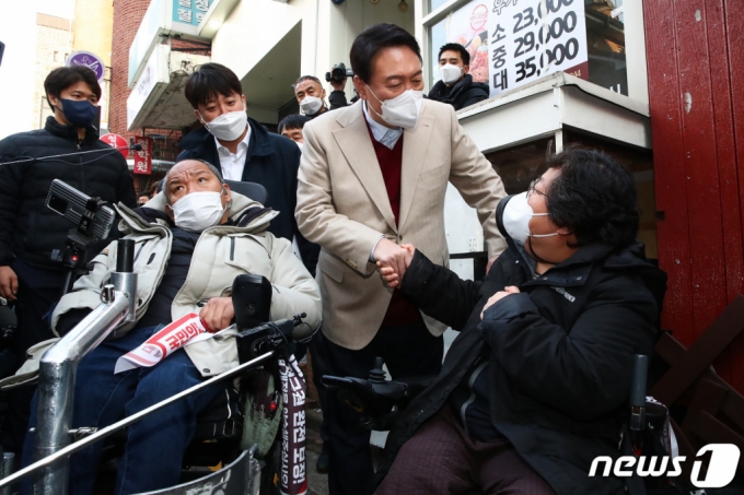 (서울=뉴스1) 국회사진취재단 = 국민의힘 윤석열 대선 후보(오른쪽)와 이준석 대표가 8일 오후 서울 종로구 대학로 거리 플렛폼74에서 열린 청년문화예술인간담회에 참석하기 전 입구에서 윤 후보와 면담을 요구하던 장애인 단체 회원과 대화하고 있다. 2021.12.8/뉴스1  