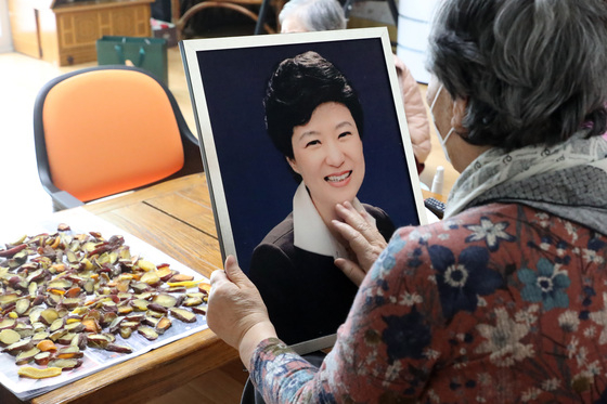 (대구=뉴스1) 공정식 기자 = 박근혜 전 대통령 특별 사면 소식이 전해진 24일 오후 대구의 한 경로당에서 할머니가 박 전 대통령 존영을 어루만지고 있다. 80대 A씨 부부는 박 전 대통령 탄핵 이후 지난 4년9개월간 자신의 집 안방에 사진을 보관해왔다고 말했다. 2021.12.24/뉴스1  