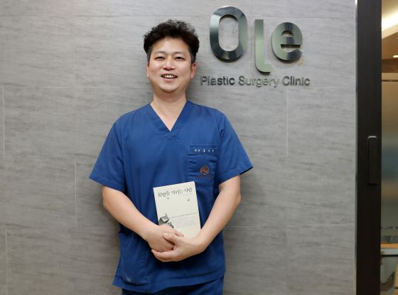 바이오포스 홍기석 대표가 '꿀벌을 지키는 사람들'이란 제목의 책자를 들고 사진 포즈를 취하고 있다/사진=김휘선 기자