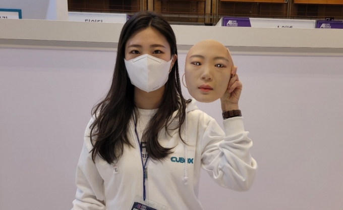 씨유박스 관계자가 AI엑스포에서 3D 얼굴 위조 마스크를 들고 있다. 씨유박스는 얼굴 위변조 여부를 AI로 밝혀낼 수 있는 보안 인증 솔루션을 이번 박람회에서 선보인다/사진제공=씨유박스