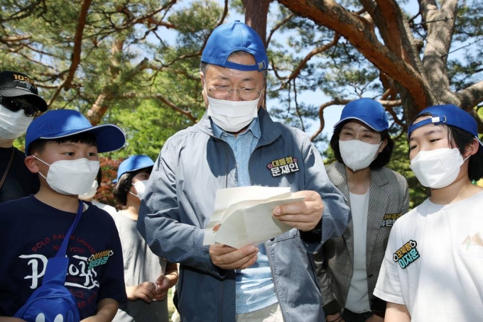 [서울=뉴시스] 전신 기자 = 문재인 대통령이 5일 청와대 녹지원에서 열린 2022년 어린이날 100주년 기념 청와대 어린이 초청행사에서 어린이들에게 받은 편지를 읽고 있다. 2022.05.05.