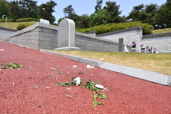 18일 오후 광주 북구 운정동 5·18민주묘지에서 한 참배객이 대통령의 애도 화환을 훼손, 화환 속 국화가 바닥에 떨어져 있다 /사진=뉴시스 
