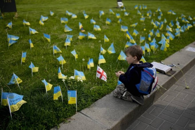 [키이우=AP/뉴시스] 23일(현지시간) 우크라이나 키이우에서 한 소년이 러시아군과 전투 중 숨진 우크라이나 군인들의 이름이 적힌 추모 국기들을 바라보고 있다. 2022.05.24.