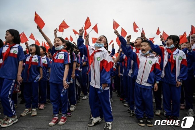 (샤오산 AFP=뉴스1) 우동명 기자 = 27일(현지시간) 후난성 샤오산 광장에서 공산당 창당 100주년을 앞두고 학생들이 국기를 흔들며 환호를 하고 있다.   (C) AFP=뉴스1  