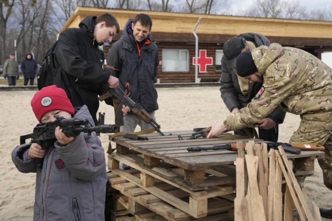 [키예프=AP/뉴시스] 20일(현지시간) 우크라이나 키예프에서 한 교관이 우크라이나 극우 단체회원들에게 AK47 소총에 관해 설명하는 동안 한 소년이 소총을 들고 놀고 있다. 러시아가 우크라이나 동부 돈바스 지역의 상황 악화를 구실로 20일 종료 예정이던 벨라루스와의 합동 군사훈련을 연장해 우크라이나 침공에 대한 긴장이 고조되고 있다. 2022.02.21.