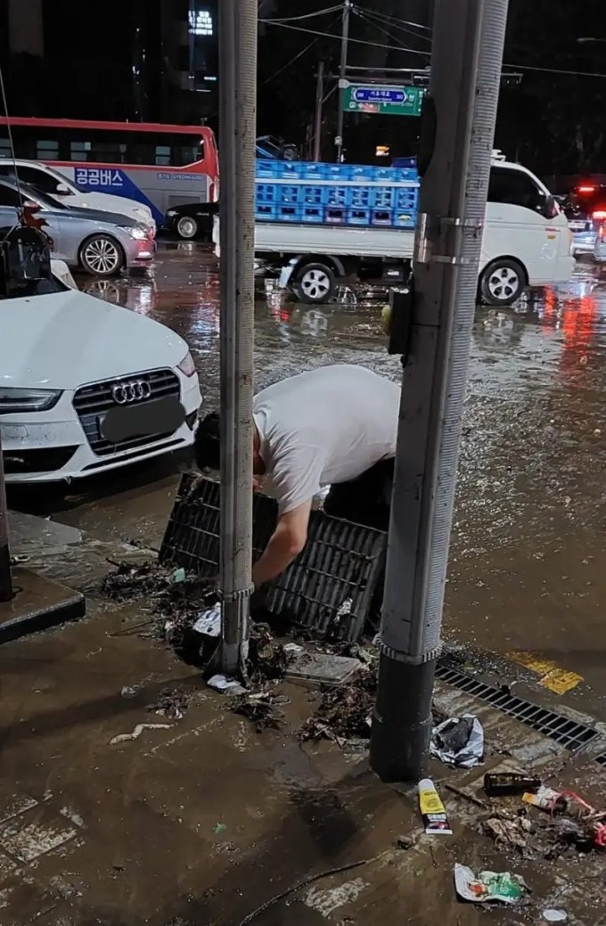 한 남성이 8일 강남역 근처에서 빗물받이 덮개를 열고 안에 있는 쓰레기를 맨손으로 건져내고 있다 /사진=온라인 커뮤니티