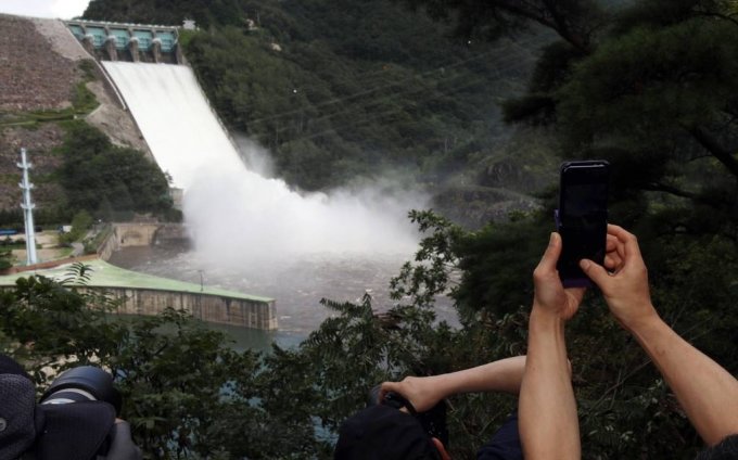  11일 오후 시민들이 강원 춘천시 소양강댐이 보이는 야산 중턱에서 2년 만에 수문을 열고 한강으로 방류하는 소양강댐의 광경을 지켜보고 있다./사진=뉴시스