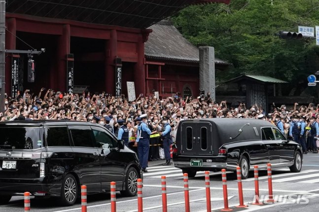 [도쿄=AP/뉴시스] 아베 신조 전 일본 총리의 시신 운구 차량(오른쪽)이 12일 일본 도쿄의 조죠지에서 장례식을 마친 뒤 조문객들의 배웅을 받으며 사찰을 떠나고 있다. 2022.07.12.