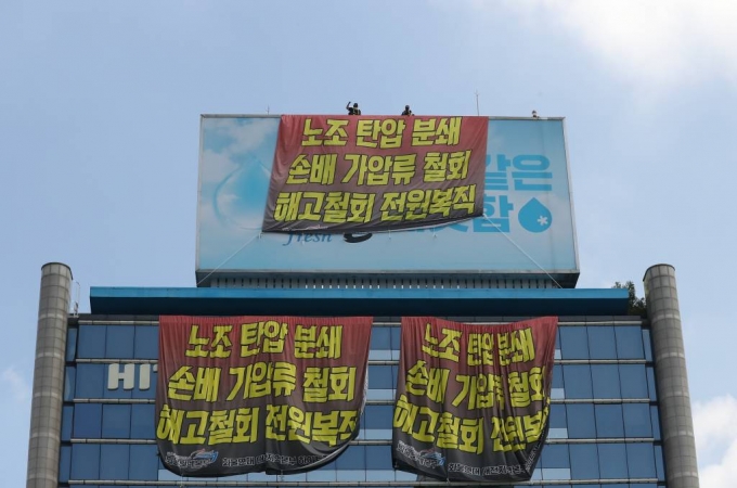 [서울=뉴시스] 김금보 기자 = 전국민주노동조합총연맹 공공운수노조 화물연대 조합원들이 16일 오전 서울 강남구 하이트진로 본사 옥상에 대형 현수막을 설치하고 점거농성을 하고 있다. 2022.08.16.