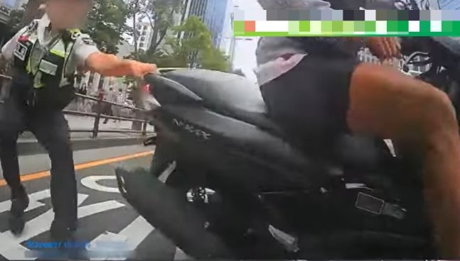 지난 8월27일 오후 4시쯤 부산 부산진구 한 도로에서 번호판 없는 오토바이를 탄 운전자가 단속을 나온 교통경찰관을 매달고 달리는 일이 벌어졌다./사진=한문철TV 