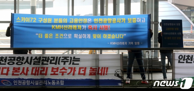 (인천공항=뉴스1) 정진욱 기자 = KMH신라레저 관계자들이 25일 오후 인천국제공항 1터미널에서 스카이 72 직원 고용안전을 보증한다는 내용의 현수막을 들어보이고 있다. 2021.3.25/뉴스1