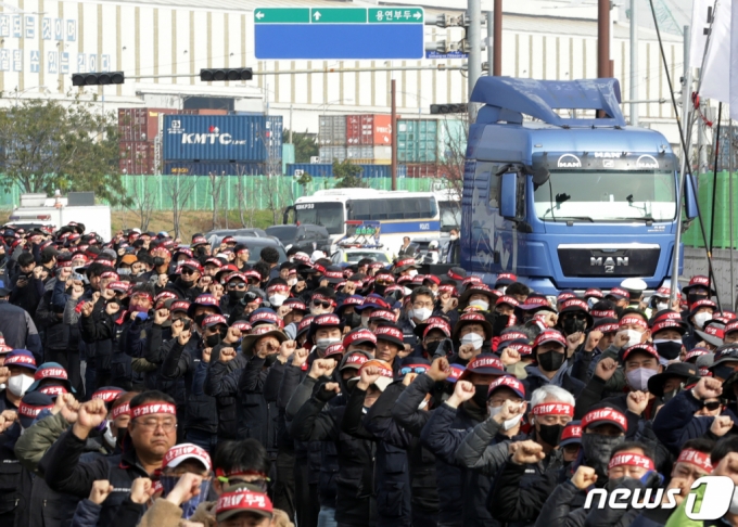 24일 울산 남구 울산신항 앞에서 민주노총 전국공공운수노동조합 화물연대 울산본부 총파업 출정식이 열린 가운데 구호를 외치는 조합원들 뒤로 화물차가 지나가고 있다. /사진=뉴스1.
