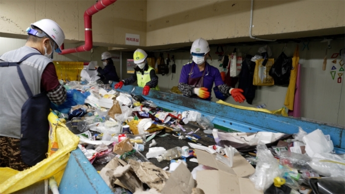 작업대에서 재활용 쓰레기를 선별하고 있는 작업자들과 정주희 기후캐스터(왼쪽에서 세번째)./사진=서울시, 이상열 미디어트립 PD
