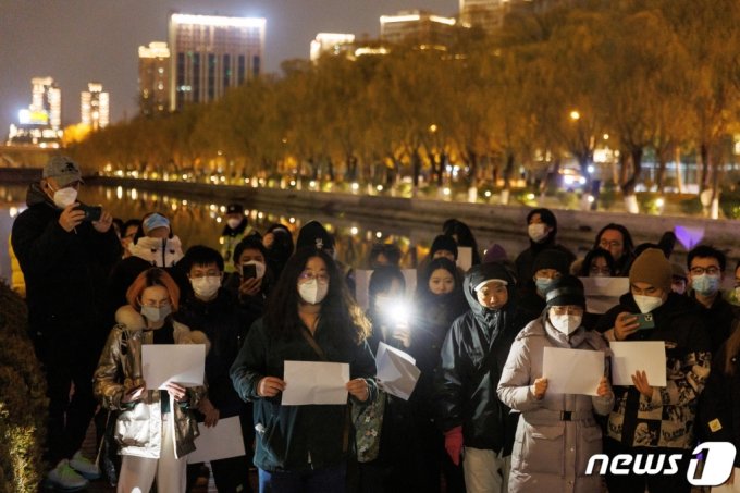 11월 27일 중국 베이징에서 열린 우루무치 화재 희생사 추모 행사에서 사람들이 정부의 코로나19 규제에 항의하기 위해 모여 흰 종이를 들고 있다. / 로이터=뉴스1 