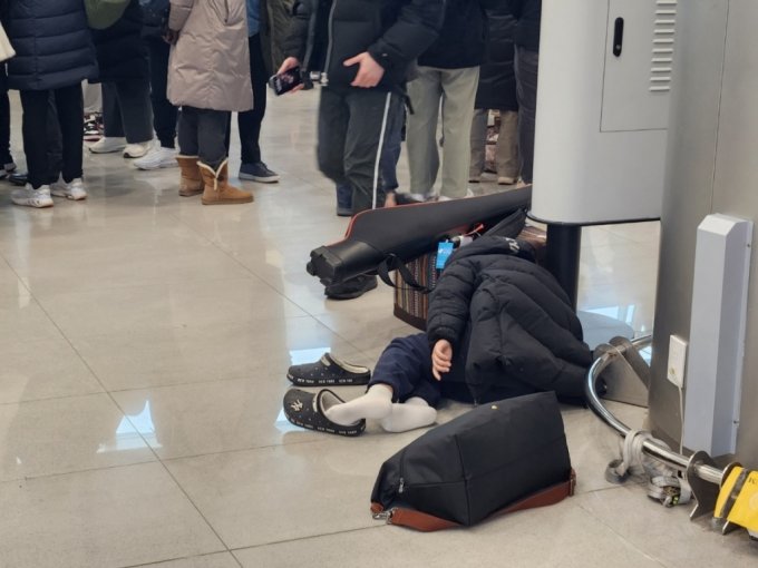 24일 오전 5시30분쯤 제주공항 3층에서 한 아이가 기다림에 지친 듯 공항 바닥에 누워있었다./사진=박상곤 기자