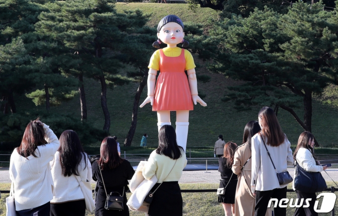 (서울=뉴스1) 박세연 기자 = 25일 오후 서울 송파구 올림픽공원 야외 88잔디마당에 설치된 넷플릭스 드라마 ‘오징어게임’ 영희 로봇 동상이 시민들 눈길을 끌고 있다. 올림픽공원은 “오늘부터 약 3개월간 영희 로봇 동상을 전시할 예정”이라고 밝혔다. 4m 높이의 영희 동상에서는 ‘오징어게임’ OST와 함께 ‘무궁화 꽃이 피었습니다’라는 드라마 속 음성도 나온다. 2021.10.25/뉴스1