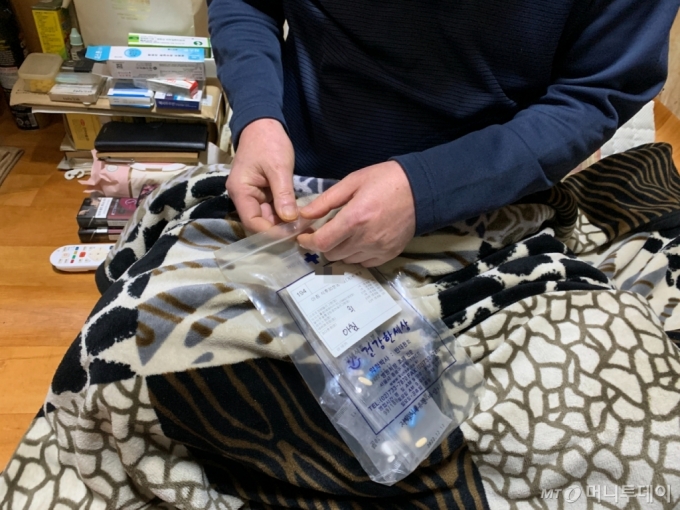 지난 27일 오전 10시 서울 용산구 동자동의 한 쪽방 내부. 쪽방 거주민 김모씨(70)가 심장약을 먹으려 하고 있다./사진=김도엽 기자