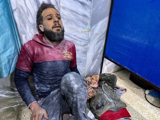 6일(현지시간) 시리아의 반군 점령 지역의 한 병원에서 지진에 살아남은 한 남성이 아이의 손을 잡고 병원 바닥에서 치료를 기다리고 있다./AFPBBNews=뉴스1