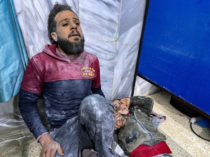 6일(현지시간) 시리아의 반군 점령 지역의 한 병원에서 지진에 살아남은 한 남성이 아이의 손을 잡고 병원 바닥에서 치료를 기다리고 있다. /ⓒAFP=뉴스1