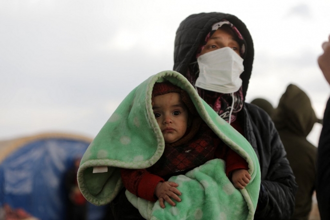 10일(현지시간) 지진 피해를 입은 시리아에서 한 여성이 아이를 안고 수색 잡업을 지켜보고 있다./AFPBBNews=뉴스1