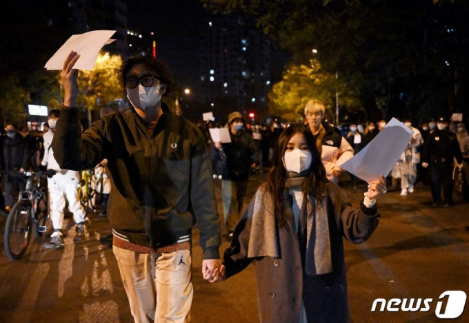 지난해 11월 28일(현지시간) 중국 베이징에서 정부의 고강도 제로 코로나19 봉쇄 정책에 항의하고 우루무치 화재 희생자를 추모하는 주민들이 정부에 항의하는 의미를 담은 ‘백지’를 들고 밤샘 시위를 하고 있다. /AFPBBNews=뉴스1
