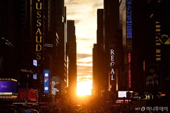 11일(현지시간) 미국 뉴욕 타임스퀘어 인근 42번가에 &#039;맨해튼헨지&#039; 현상을 보기 위해 몰려든 인파들이 사진을 찍고 있다. &#039;맨해튼헨지&#039;는 매년 5월말과 7월초 태양이 질 때 거리와 나란히 놓여 빛이 비치는 현상으로 뉴욕시의 대표적인 경치이다ⓒ 로이터=뉴스1