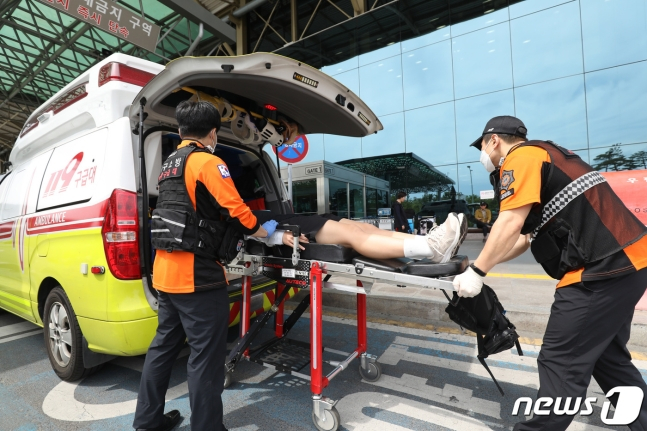 26일 오전 제주공항을 출발해 대구공항으로 향하던 아시아나 항공기에서 비행 중 문이 열리는 사고가 발생했다. 울산에서 열리는 제52회 전국소년체육대회에 참가하기 위해 비행기에 탑승했던 초·중학생 제주특별자치도 선수단 가운데 대구공항 도착 직후 고통을 호소하는 선수들을 119구조대가 병원으로 이송하기 위해 들것을 이용해 구급차로 옮기고 있다. 2023.5.26/뉴스1 ⓒ News1 공정식 기자 