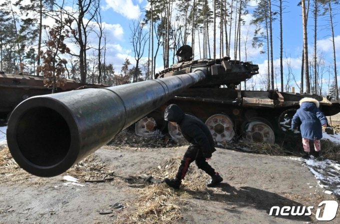 3월 6일 (현지시간) 러시아의 침공 속 우크라이나 키이우 인근 드미트리우카에서 어린이들이 파괴된 러시아 군 탱크 주변서 놀고 있다. /AFPBBNews=뉴스1