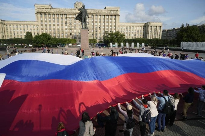 [상트페테르부르크=AP/뉴시스] &#039;러시아 국기의 날&#039;인 22일(현지시각) 러시아 상트페테르부르크에서 시민들이 블라디미르 레닌 동상 앞에 모여 대형 삼색기를 펼치고 있다. 러시아 삼색기는 소련이 붕괴한 1991년 러시아의 공식 국기가 되었고 1994년 러시아 국기의 날이 제정됐다. 2023.08.23.