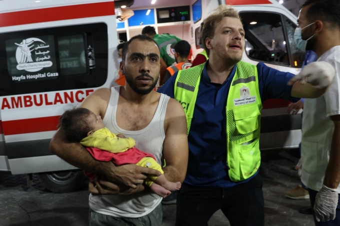 11일(현지시간) 가자지구에서 한 남성이 이스라엘 공습으로 다친 아이를 안고 병원으로 가고 있다./AFPBBNews=뉴스1