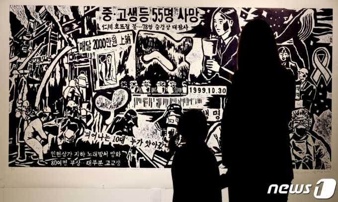 (인천=뉴스1) 정진욱 기자 = 29일 오후 인천시 중구 인천학생교육문화회관 가온갤러리에서 인현동 화재참사 21주기 추모전 ‘기억의 싹’ 전시가 열린 가운데 한 시민이 그림을 바라보고 있다.11월 7일까지 열리는 이번 추모전은 10여 명의 지역작가 및 미술교사들이 참여하여 1999년 10월 30일 인현동 상가 화재로 희생된 57명의 학생들을 추모하는 그림과 사진을 전시한다. 2020.10.29/뉴스1