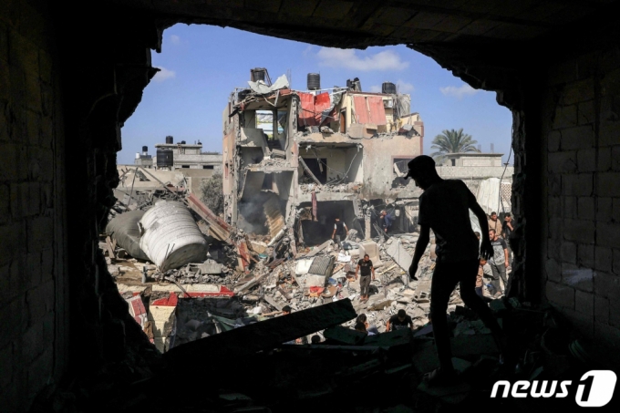 (칸유니스 AFP=뉴스1) 최종일 기자 = 이스라엘과 팔레스타인 가자지구를 통치하고 있는 무장정파 하마스 간 전쟁이 지속되고 있는 가운데 8일(현지시간) 가자지구 남부 칸유니스 캠프에서 한 남성이 이스라엘의 포격으로 벽면에 큰 구멍이 생긴 건물 앞을 지나고 있다. 다른 주민들은 무너진 건물 잔해 속에서 생존자들 수색하고 있다. ⓒ AFP=뉴스1 Copyright (C) 뉴스1. All rights reserved. 무단 전재 및 재배포, AI학습 이용 금지.