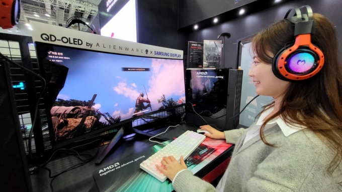 국제 게임 전시회 '지스타 2023 AMD' 부스에 전시된 '에일리언웨어 34 커브드 QD-OLED 게이밍 모니터'로 대규모 이용자 간 대전 '워헤이븐'을 체험하는 모습. / 사진 = 삼성디스플레이 제공