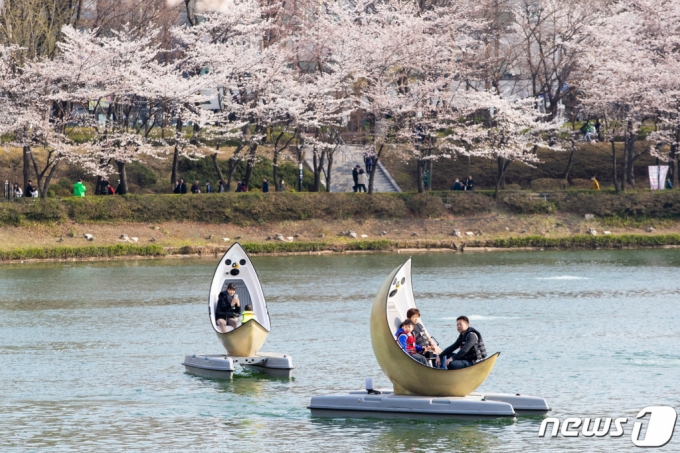 (서울=뉴스1) = 지난 27일 서울 송파구 롯데월드를 찾은 관람객들이 문보트를 타며 벚꽃이 만개한 석촌호수를 바라보고 있다. (롯데월드 어드벤처 제공) 2023.3.28/뉴스1  Copyright (C) 뉴스1. All rights reserved. 무단 전재 및 재배포 금지.