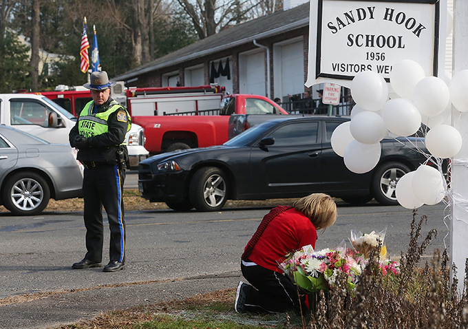  2012년 12월 14일 미국 코네티컷 주 뉴타운의 샌디훅 초등학교에서 총기 난사 사건이 발생한 다음날 소방서 밖의 임시 추모비에서 한 여성이 무릎을 꿇고 있는 모습. /AFPBBNews=뉴스1