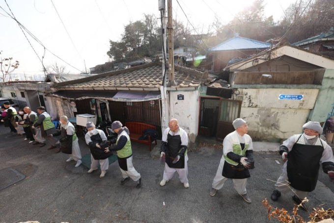 [서울=뉴시스] 홍효식 기자 = 22일 서울 성북구 정릉3동 정릉골에서 열린 &#039;자비실천, 에너지 취약계층 연탄지원&#039; 행사에서 봉사자들이 연탄을 전달하고 있다. 2023.11.22.