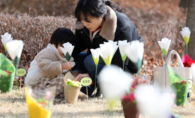 18일 대구 동구 시민안전테마파크에서 열린 2·18 대구지하철 화재 참사 21주기 추모식을 찾은 어린이가 추모 꽃밭에 꽃을 꽂고 있다. /사진=뉴시스