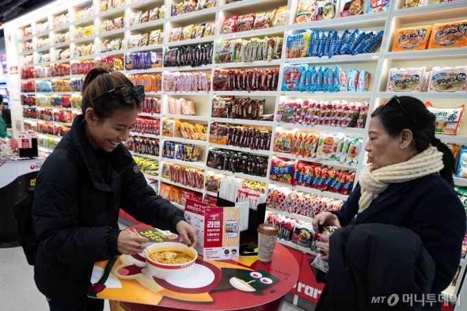 서울 마포구 CU홍대상상점에 마련된 '라면 라이브러리'를 찾은 외국인 관광객들이 라면을 조리해 옮기고 있다. 매장 내에 즉석 라면 조리기와 컵라면 모양을 본 뜬 스탠딩 시식대도 마련됐다. /사진제공=뉴스1