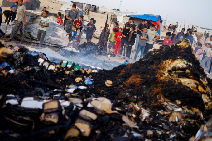 27일(현지시간) 가자지구 최남단 라파의 텔 알술탄 난민촌에서 피란민들이 이스라엘군 공습에 불타버린 구호품을 쳐다보고 있다. 이 공습으로 최소 45명이 숨진 것으로 알려졌다. 2024.05.27 /로이터=뉴스1