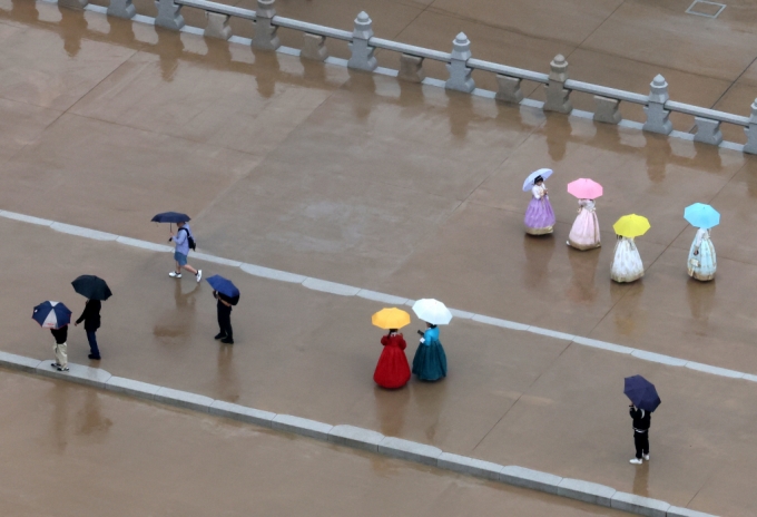 서울 종로구 광화문 월대에서 우산을 쓴 관광객들이 기념사진을 찍고 있다./사진=뉴시스