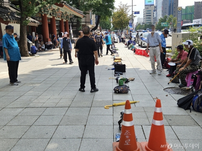 12일 오전 서울 종로구 탑골공원 삼일문 앞에 무료 급식소를 이용하기 위한 고령자들이 도착 순서대로 바닥에 소지품을 내려 놓은 모습. 폭염에 더위를 피하기 위해 직접 줄을 서는 대신 소지품을 늘어 놓은 것이다. /사진=정세진 기자 