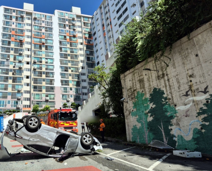  12일 부산 사상구 한 아파트에서 주차하기 위해 후진하던 승용차가 경로당 건물을 들이받은 뒤 난간을 뚫고 약 10m 아래로 추락했다. 이후 승용차는 아래 도로를 지나던 승합차 보닛 부분으로 떨어진 뒤 전복됐다. /사진=뉴시스(부산소방재난본부 제공)